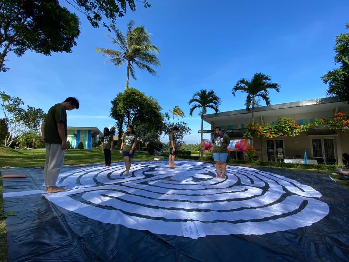 Peserta berjalan di labirin di luar ruangan di bawah langit biru selama retret kontemplatif