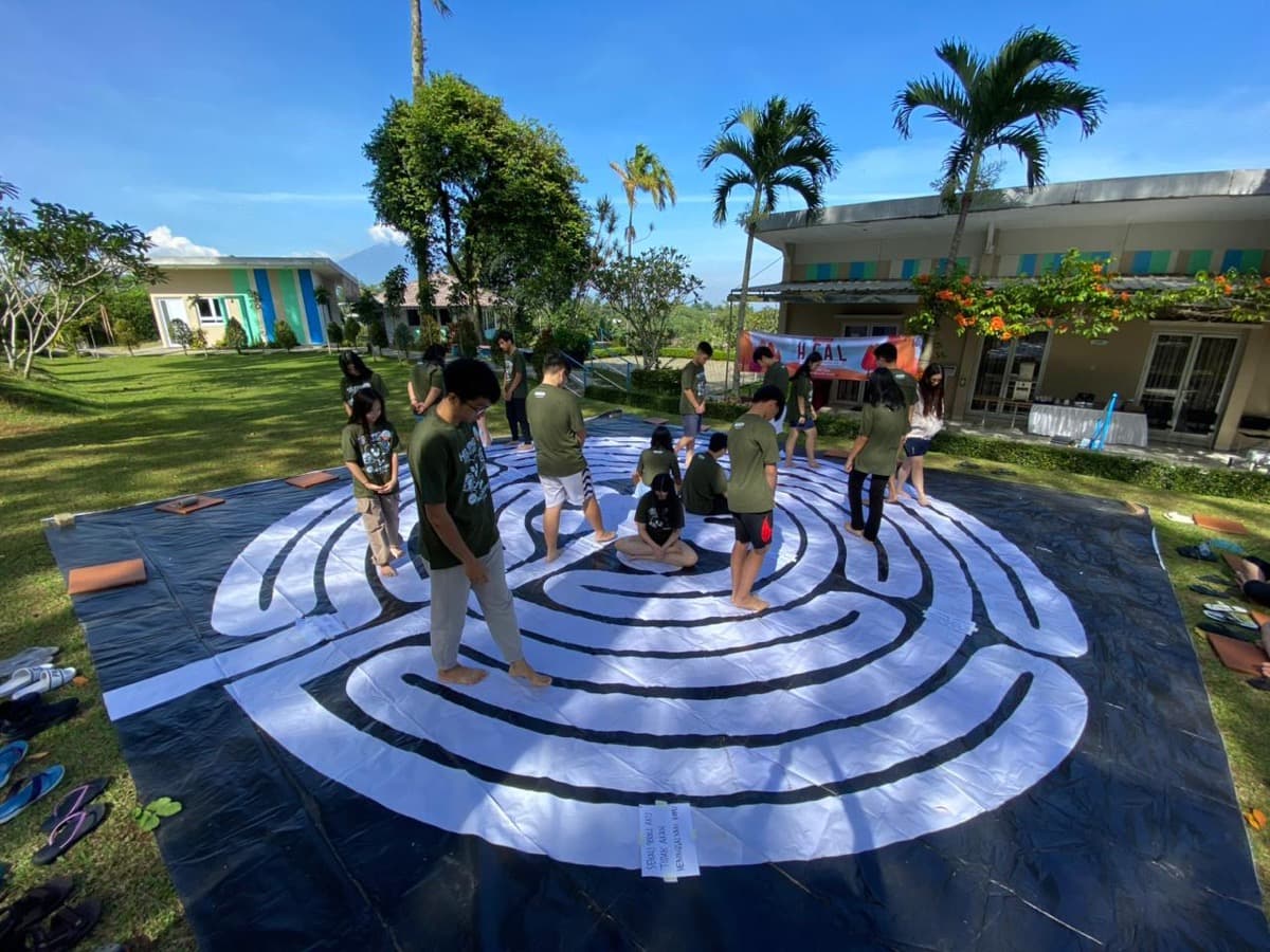 Kelompok berkumpul di labirin dengan pohon kelapa di latar belakang