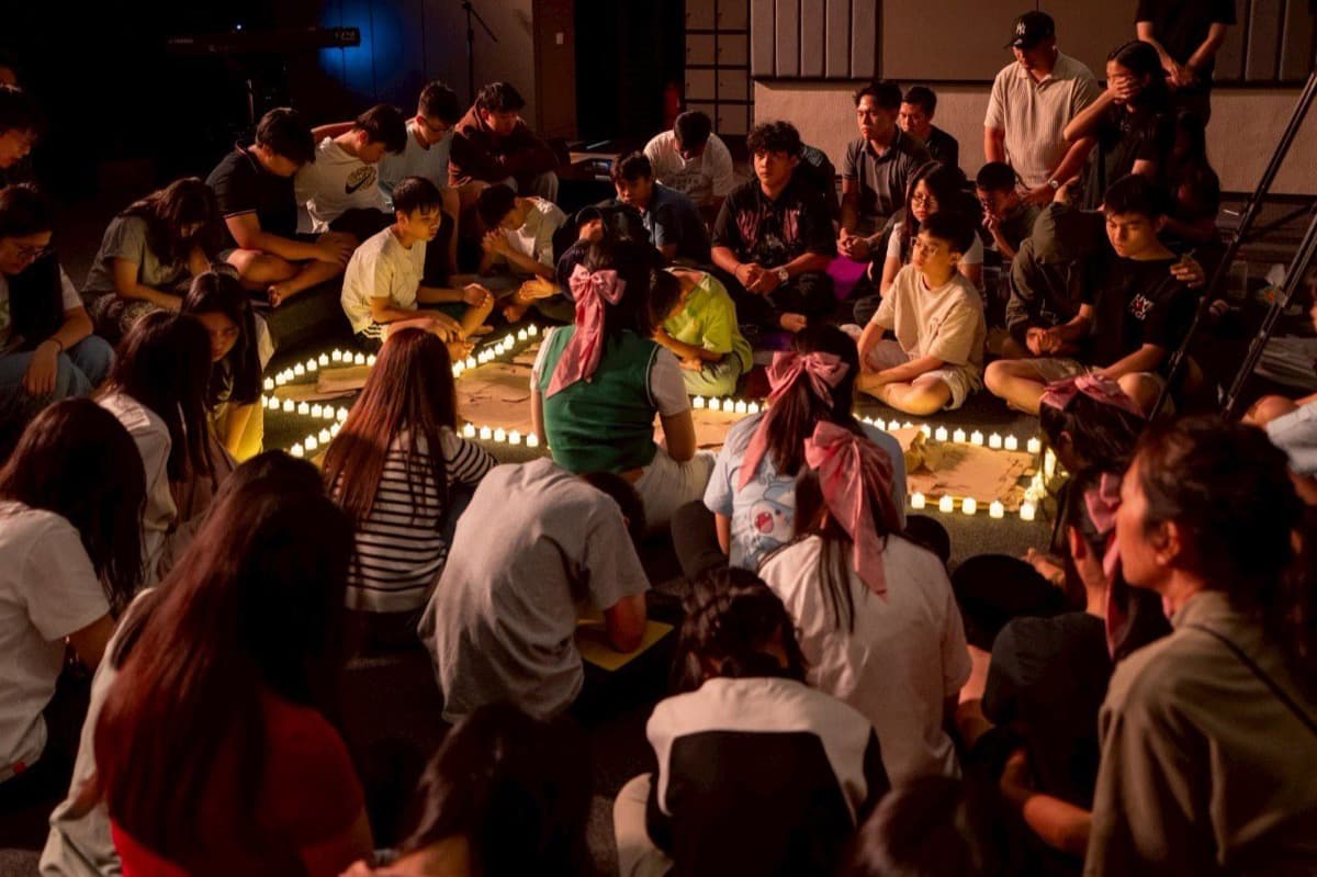 Kelompok besar duduk dalam lingkaran cahaya lilin selama sesi retret kontemplatif